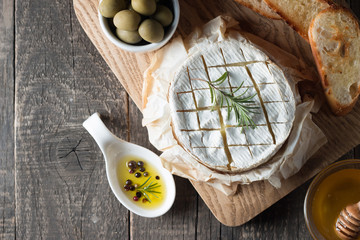 Camembert and brie cheese on wooden background with tomatoes, letuce and garlic. Italian food. Dairy products.