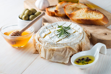 Camembert and brie cheese on wooden background with tomatoes, letuce and garlic. Italian food. Dairy products.