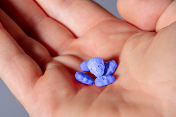 Close-up of a caucasian handpalm with blue MDMA, Amphetamine, Army Skull, Ecstasy or XTC pills.