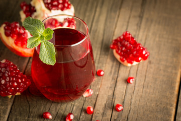 Pomegranate juice with fresh pomegranate fruits on wooden background. soft drink with lime, mint and ice.