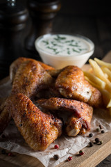 Barbecue grilled chicken wings close up with fries, tomato ketchup sauce and beer on wooden background. Meat food concept. 