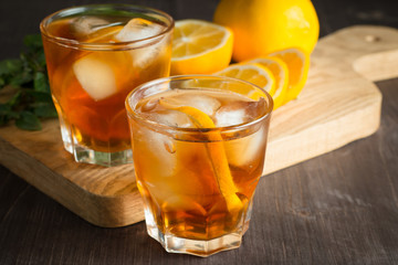 Glasses of cold ice tea with lemon, ice, mint on background. Homemade lemonade. Spring and summer drinks and beverages concept. 