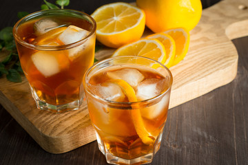 Glasses of cold ice tea with lemon, ice, mint on background. Homemade lemonade. Spring and summer drinks and beverages concept. 
