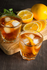 Glasses of cold ice tea with lemon, ice, mint on background. Homemade lemonade. Spring and summer drinks and beverages concept. 