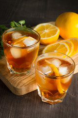 Glasses of cold ice tea with lemon, ice, mint on background. Homemade lemonade. Spring and summer drinks and beverages concept. 