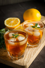 Glasses of cold ice tea with lemon, ice, mint on background. Homemade lemonade. Spring and summer drinks and beverages concept. 