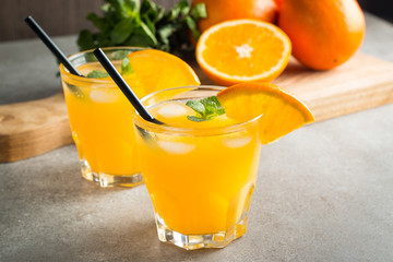 Photo of fresh orange juice in the glass jar. Summer healthy organic drink concept. Cold beverages with ice and orange fruits.