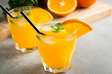 Photo of fresh orange juice in the glass jar. Summer healthy organic drink concept. Cold beverages with ice and orange fruits.