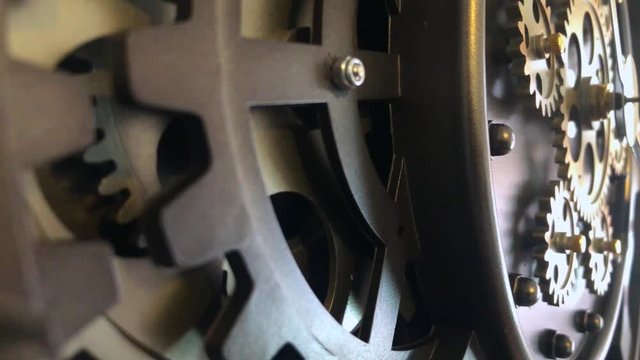 Close up shallow view from left to right in slow motion of vintage clockwork cogs and mechanism as it rotates in unison.