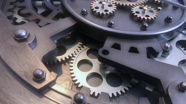 Close up shallow angle view of vintage clockwork cogs and mechanism as it rotates in unison.