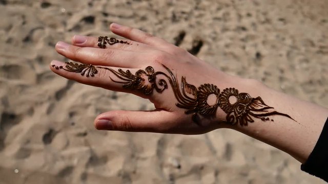 Rotating shot of henna tattooed newly done in sandy beach Persian gulf Rotating shot of an eastern girls hand newly henna tattoo done sandy beach white skin