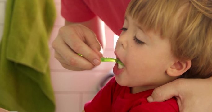 Father brushing his son's teeth in bathroom morning close-up