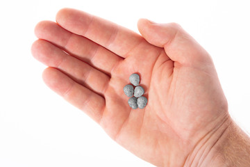 Top view of a caucasian hand with grey MDMA, Amphetamine, Army Skull, Ecstasy or XTC pills on a white background..