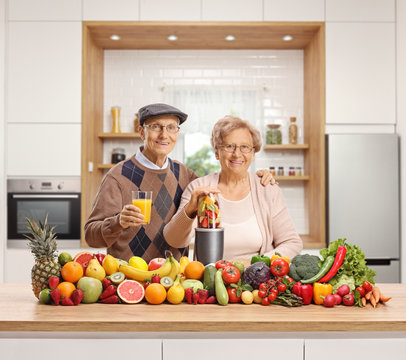 Elderly husband and wife with a pile of fruits and vegetables and a blender - Powered by Adobe