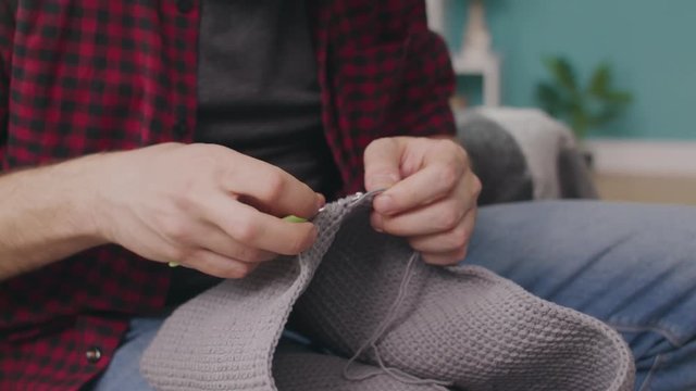 Handheld close up shot of man hands knitting