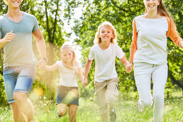 Fototapeta premium Junge läuft mit Familie über Sommer Wiese