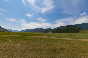 Altai Mountain valley with white clouds. Summer time. Rural car road.