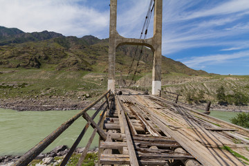 Old wooden Bridge on  iron ropes through the Katun River. Summer sunny time. Close up.
