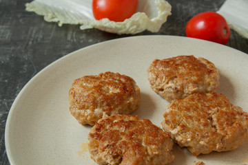 Homemade juicy minced meat patties burgers in a plate close up and fresh tomatoes with lettuce leaves