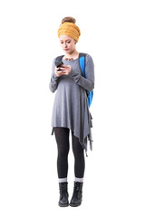Young hipster backpacker woman adventurer using smart phone carrying rucksack. Full body isolated on white background. 