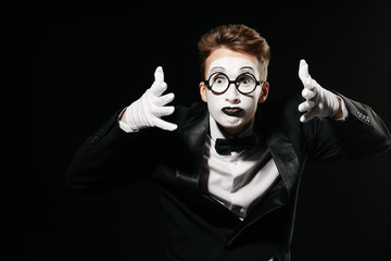 portrait of mime man in tuxedo and glasses screaming on black background