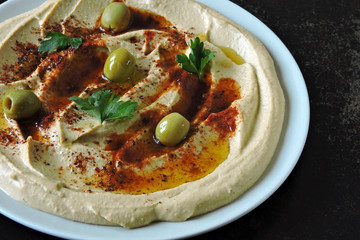 Hummus on a plate with paprika, olive oil and olives. Fresh homemade classic hummus. Middle Eastern cuisine.