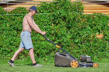 Country works on the personal plot using lawn mower. © Artem
