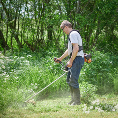 Obraz premium Country works on the personal plot using grass trimmer.