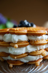 Homemade waffles with aronia, eggs and lilac flowers on the wooden table