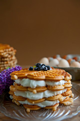 Homemade waffles with aronia, eggs and lilac flowers on the wooden table
