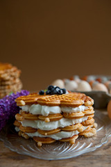 Homemade waffles with aronia, eggs and lilac flowers on the wooden table