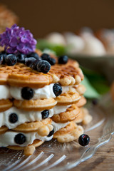 Homemade waffles with aronia, eggs and lilac flowers on the wooden table