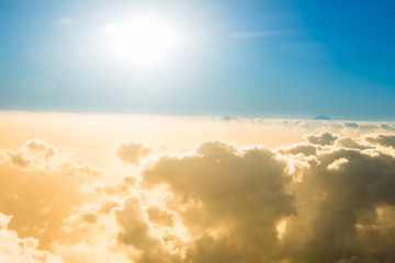 Airplane view of clouds, ocean and bright sun