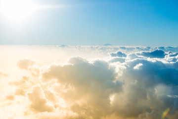Airplane view of clouds, ocean and bright sun