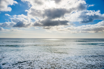 Obraz premium Seascape with silver sunlight reflection, sky and clouds