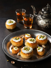 Kataifi, kadayif, kunafa, baklava pastry nests cookies with pistachios with tea. Cooking sweets turkish, or arabic traditional ramadan pastry dessert on a dark background.