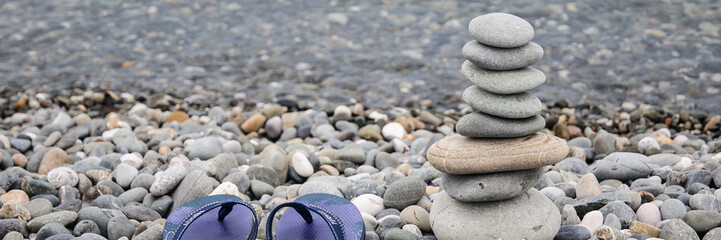 Fototapeta na wymiar Pyramid of sea stones on pebbles of the sea shore. Seascape. The concept of balance and spirituality.