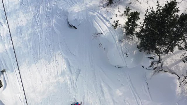 Aerial top view of a snowboarder riding from powder snow hill very fast and falling down. Footage. Man boarder jumping from a hill and falling down, sport concept.