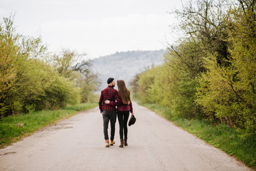 Obraz premium A couple walking by the road at the country side. Back view