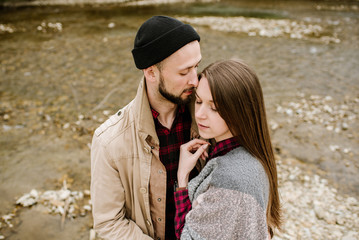 Fototapeta premium Young travelers couple hugs each other on the mountain river on the background