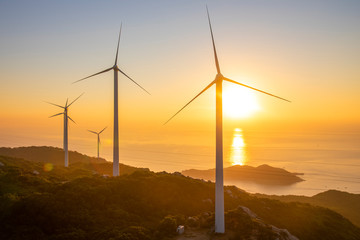 Fototapeta na wymiar Wind turbines on the mountains are on the beach at sunrise and sunset.