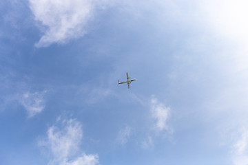 Airplane flying in the blue sky among clouds and sunlight