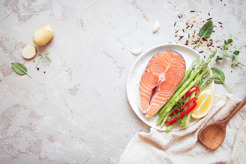 Raw salmon steak with fresh vegetables for garnish.