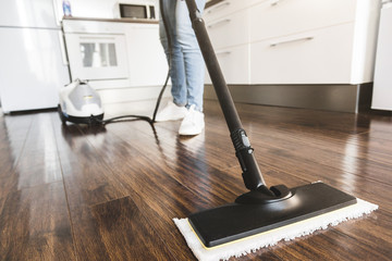 professional home cleaning service. Woman washes the floor with a steam mop