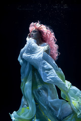 Fototapeta na wymiar woman with pink hair in white dress underwater. Mermaid, nymph or drowning in white dress under water