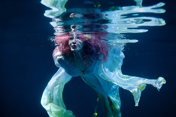 woman with pink hair in white dress underwater. Mermaid, nymph or drowning in white dress under water