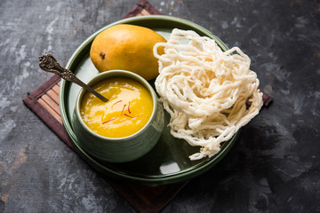 Aam Ras or Alphonso mango pulp with kurdai which is a fried dish made using wheat/gehu. selective focus