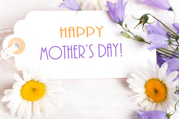 Mothers day card with with a bouquet of delicate wildflowers campanula on white wooden board