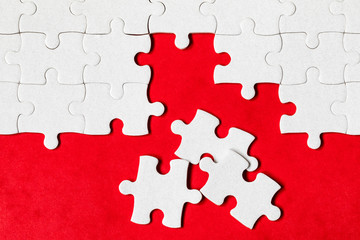 Unfinished white jigsaw puzzle pieces. Fill in pieces of the jigsaw puzzle. Complete the jigsaw puzzle with the missing pieces. Fragment of a folded white jigsaw puzzle.