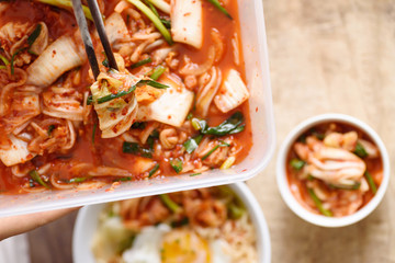 Kimchi cabbage in the plastic box with chopsticks and noodles, Korean food